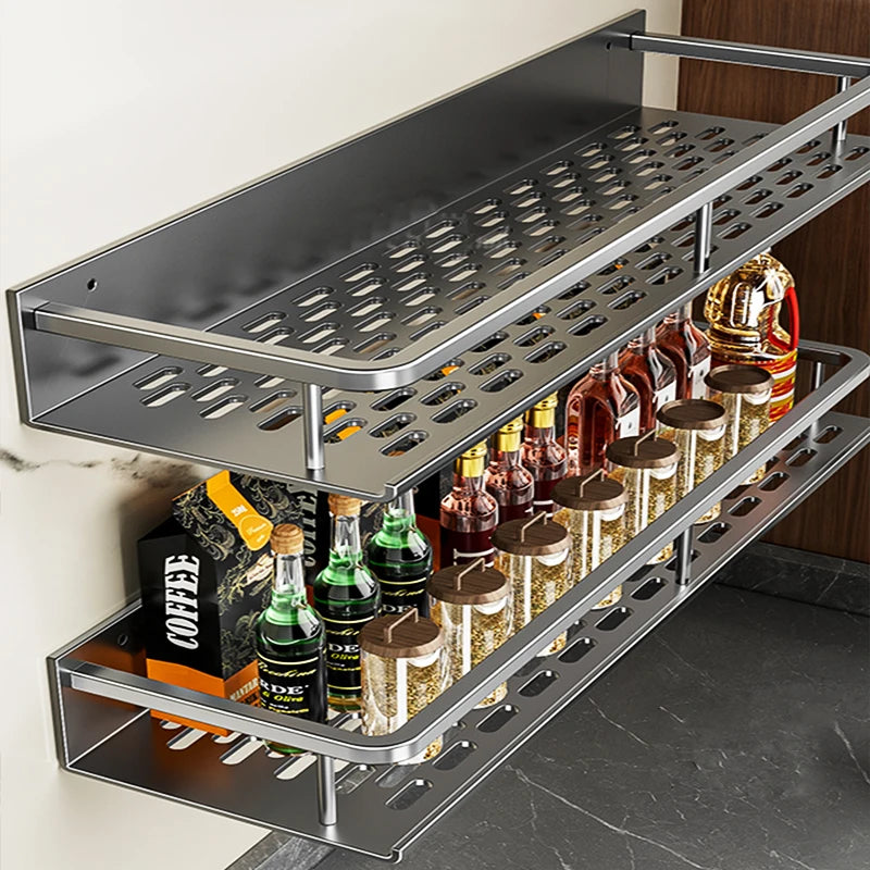 Wandgemonteerd metalen keukenrek met twee geperforeerde planken, gevuld met glazen flessen, kruidenpotjes en een doos koffie, geplaatst tegen een lichte muur in een moderne keuken.
