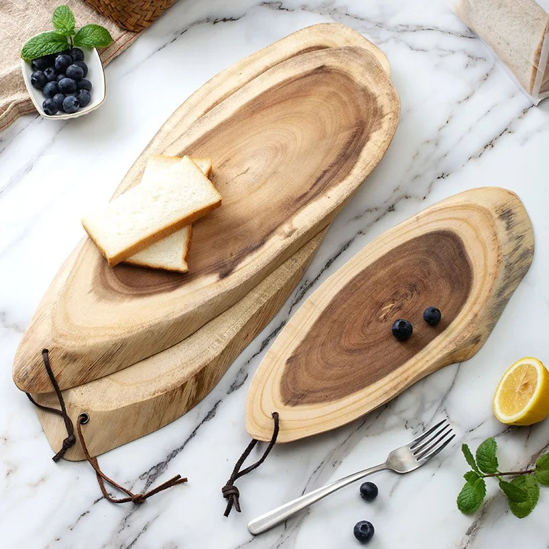 Luxe ovale snijplanken van acaciahout met natuurlijke houtnerf, gebruikt voor serveren van brood en fruit op een marmeren keukenblad.