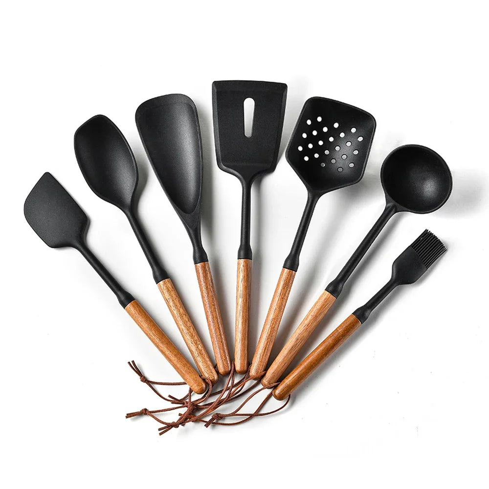 Set van zeven zwarte siliconen keukenhulpen met houten handvatten en leren ophanglussen, inclusief spatel, opscheplepels, bakspaan, schuimspaan, soeplepel en keukenkwast, gepresenteerd op een witte achtergrond. Ideale keukentools voor dagelijks koken en bakken.