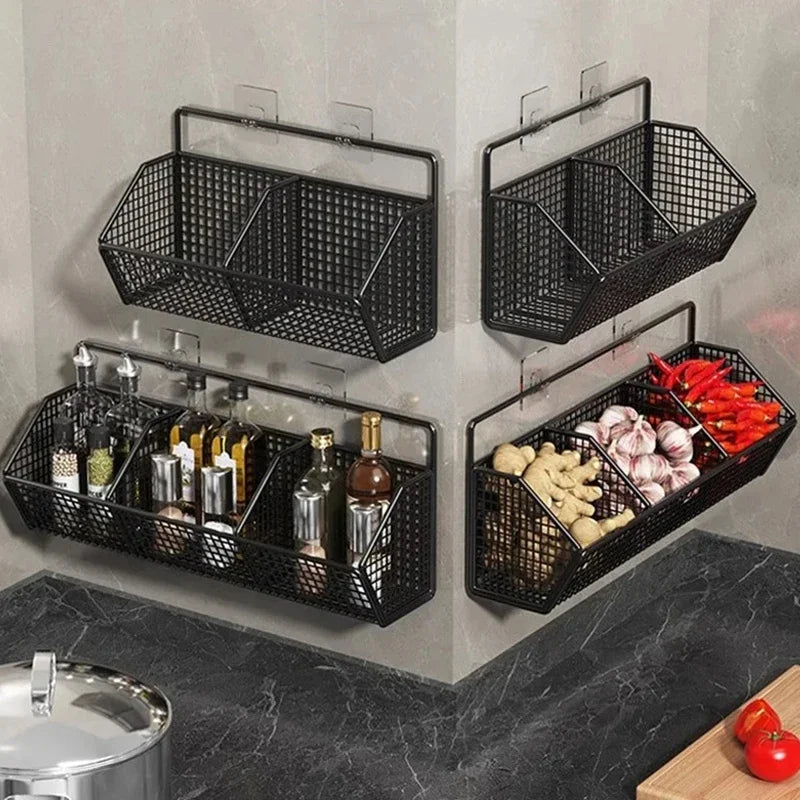 Zwarte metalen wandmanden voor keukenopslag, bevestigd aan de muur met haakbeugels, gevuld met kruidenflessen, knoflook, gember en rode pepers.